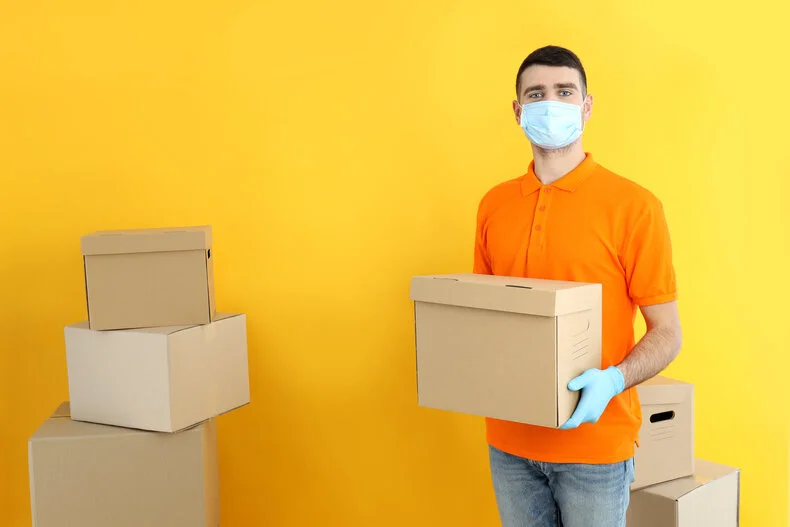 young man carrying a package with gloves and mask on